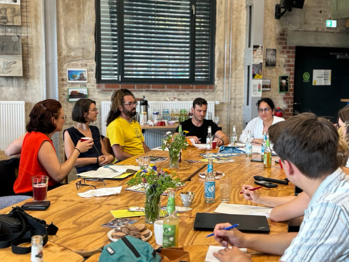 Besuch von der Unabhängigen Bundesbeauftragten für Antidiskriminierung, Ferda Ataman, in Görlitz: Ferda Ataman und Projektmitarbeitende sitzen an einem langen Konferenztisch in Görlitz.