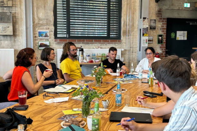 Projektmitarbeitende an einem großen Konferenztisch mit Ferda Ataman, der Antidiskriminierungsbeauftragten des Bundes, zu Besuch in Görlitz